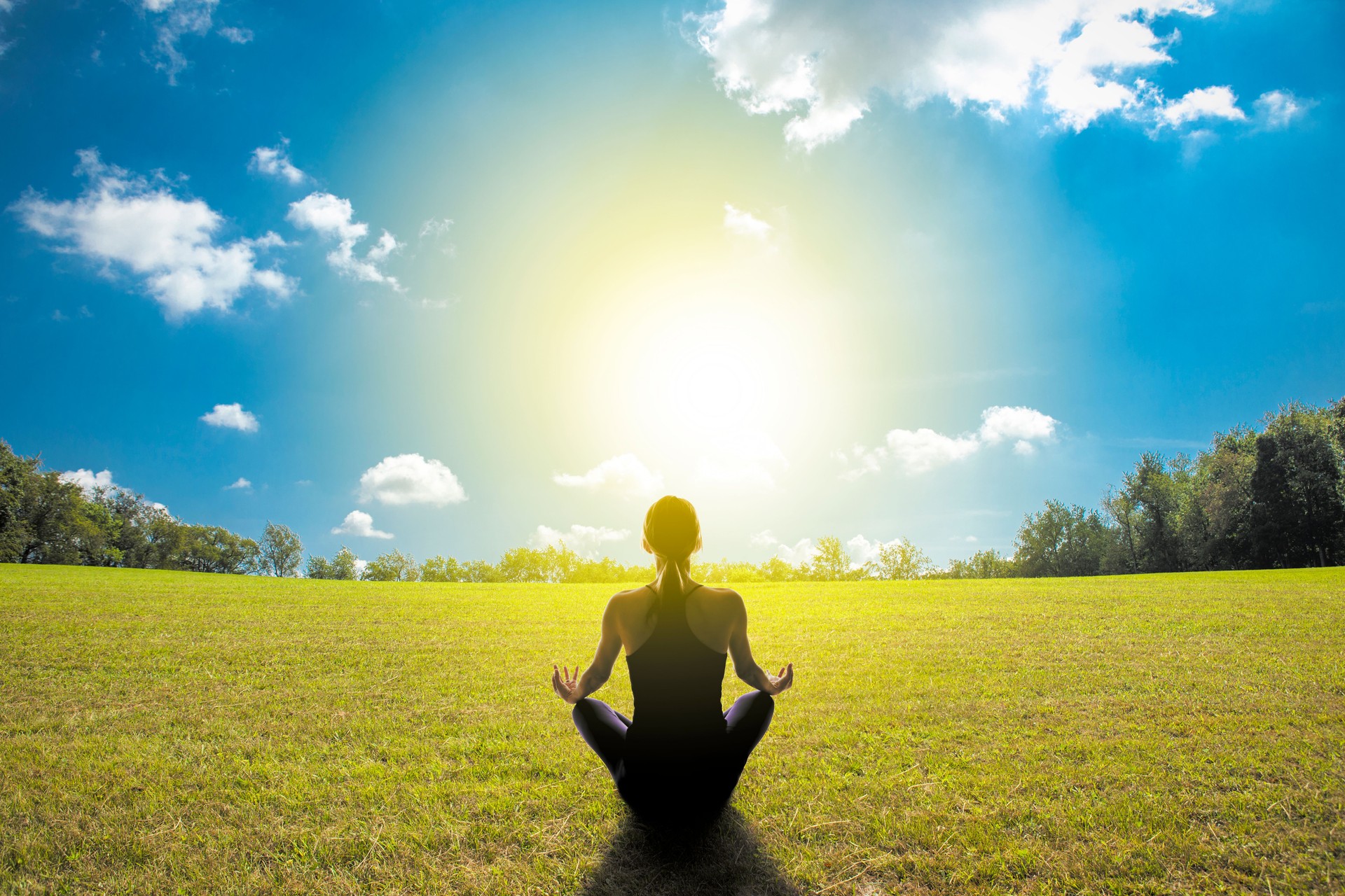 Woman Meditating in Open Grass Field on Sunny Day